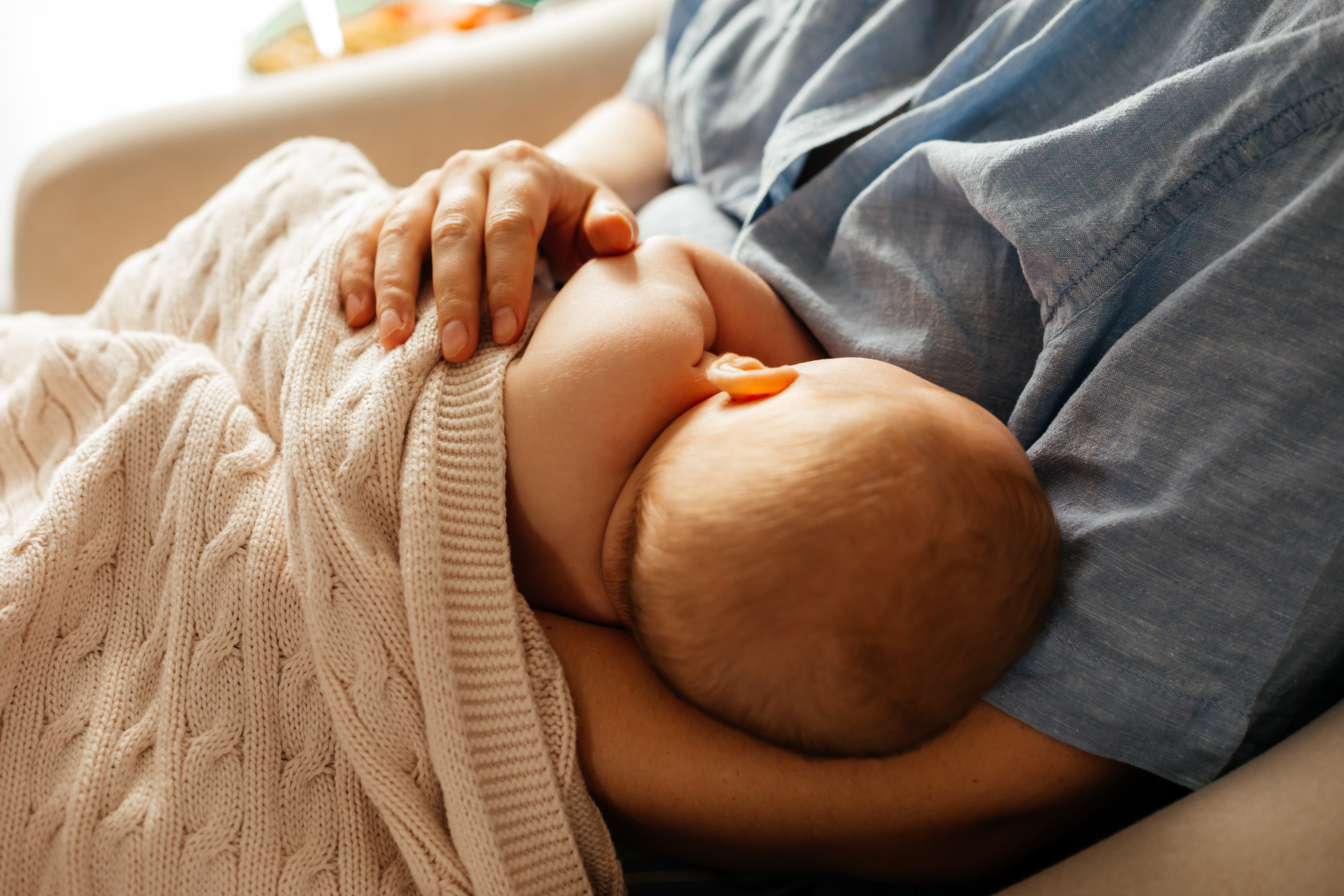 Midsection Of Mother Breastfeeding Baby At Home